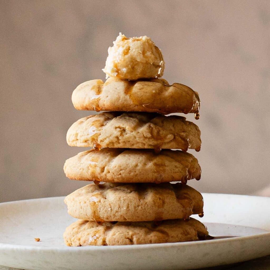A stack of Crumbl waffle cookies with frosting and maple syrup