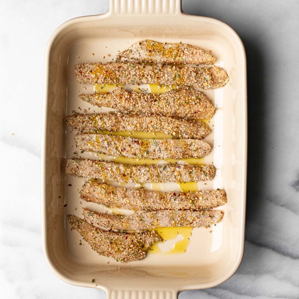 chicken tenderloins in a baking dish before they are baked