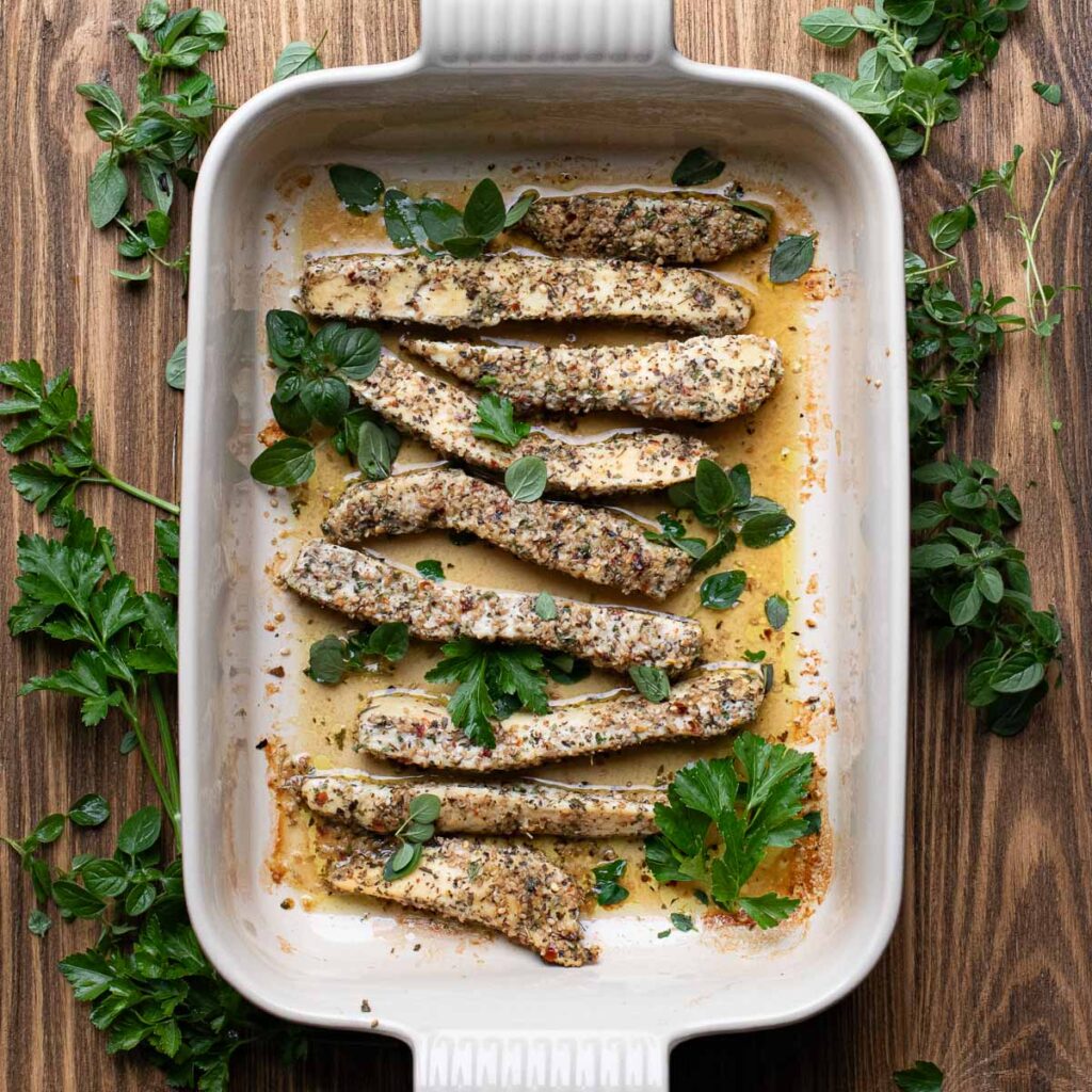 baked Italian chicken tenders in a baking dish with fresh herbs