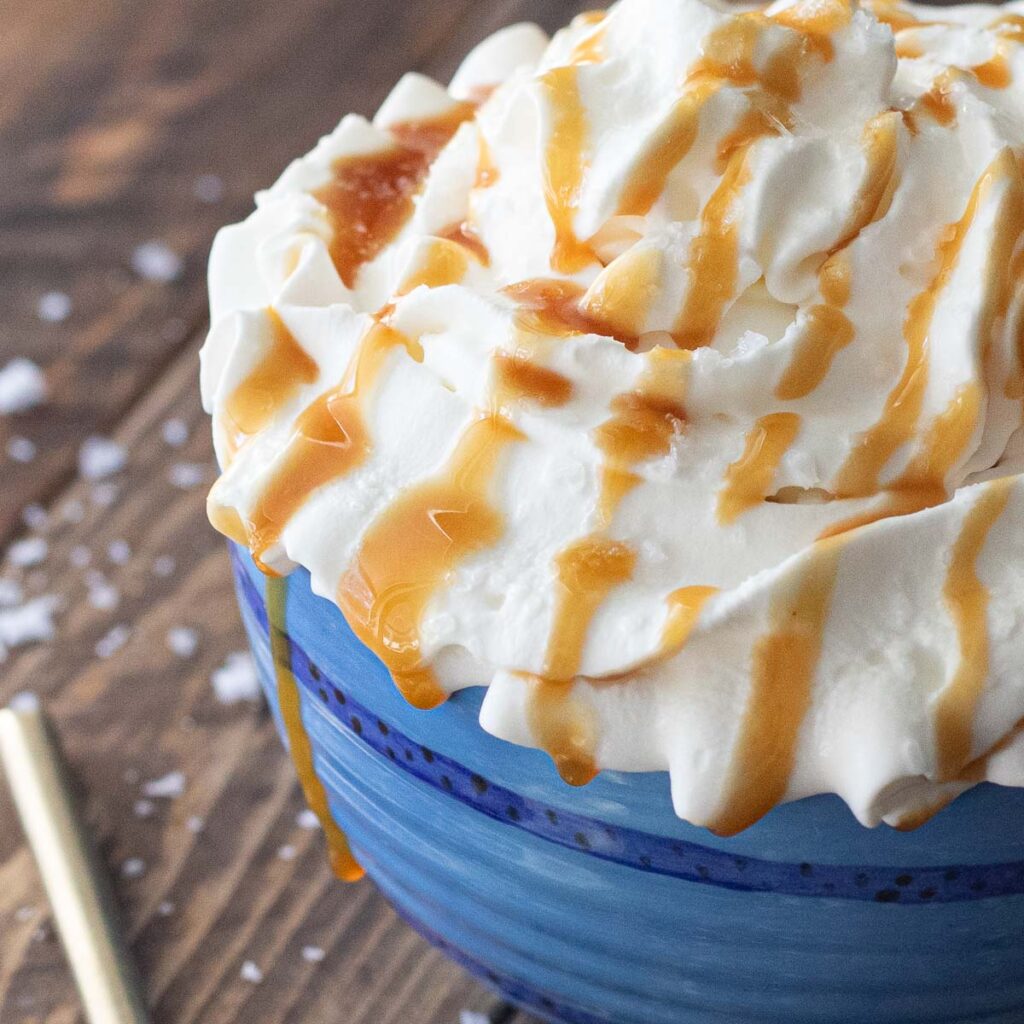 whipped cream on top of a coffee mug with caramel sauce dripping down