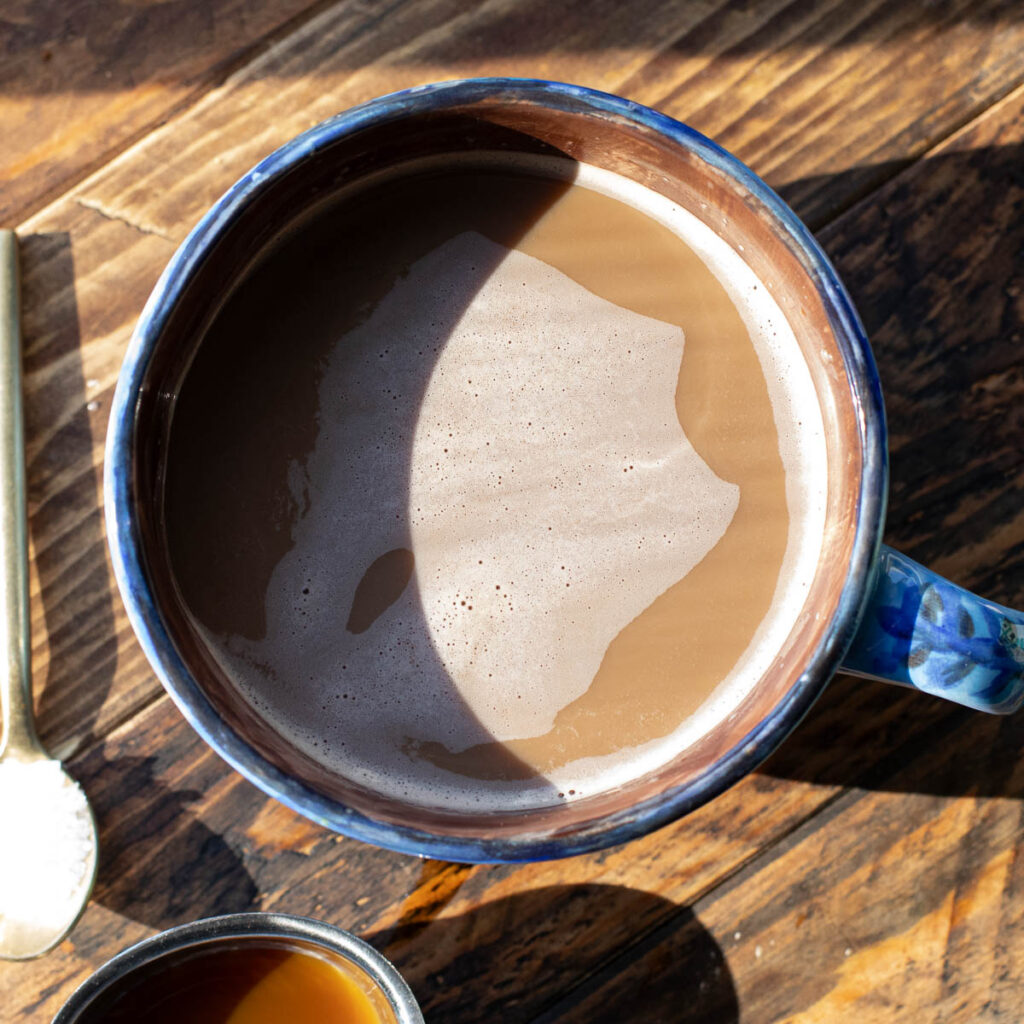 hot coffee in a blue mug with sun shining on it