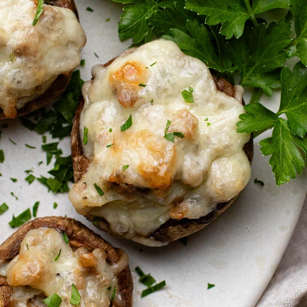 sausage stuffed mushrooms on a  white plate with fresh parsley