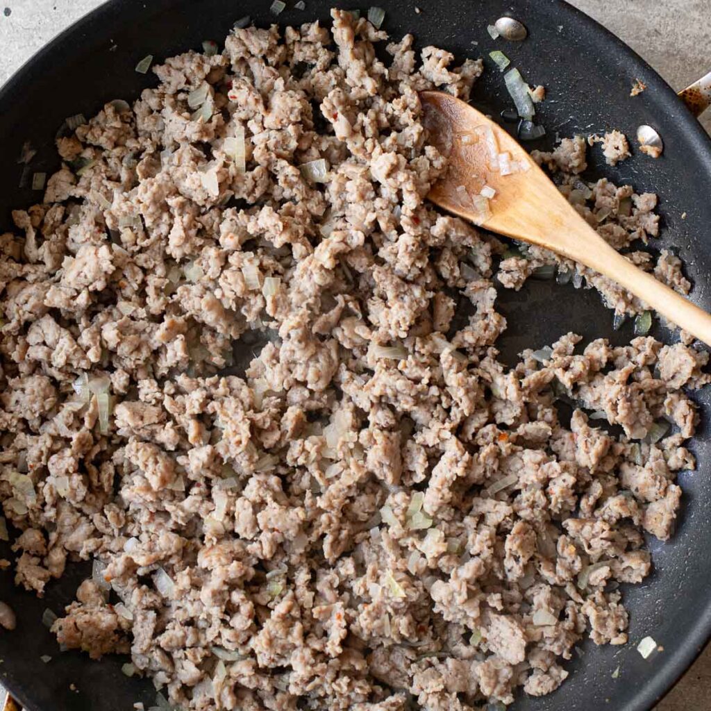 ground sausage and onions cooking in a pan