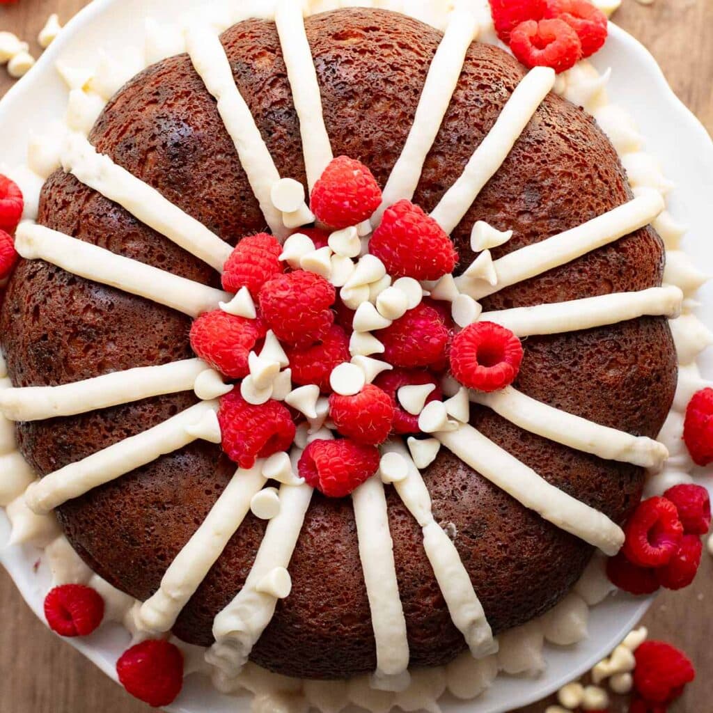 White chocolate raspberry bundt cake topped with fresh raspberries and white chocolate chips