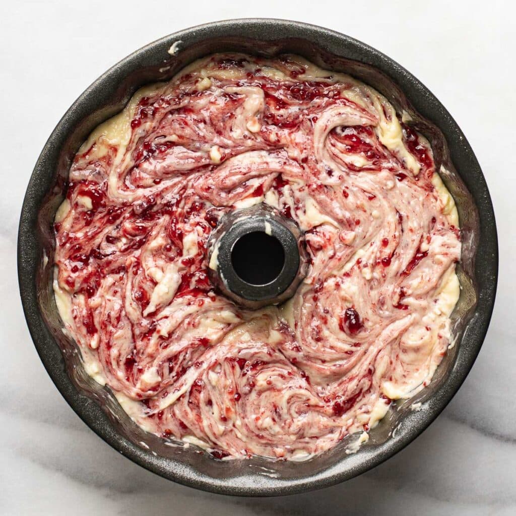 cake batter and raspberry jam swirled together in a bundt pan