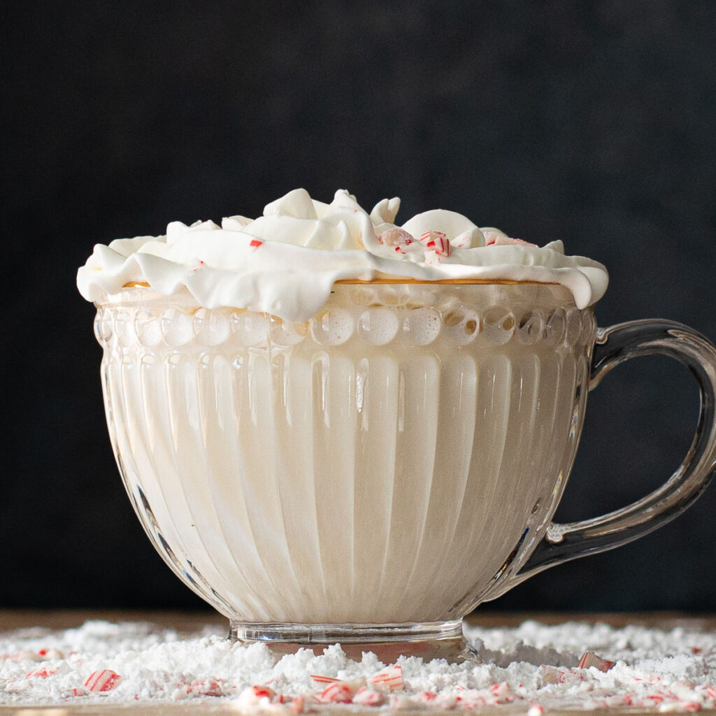 white hot chocolate topped with whipped cream in a glass mug
