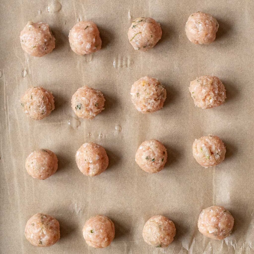 chicken meatballs on parchment paper before they are cooked