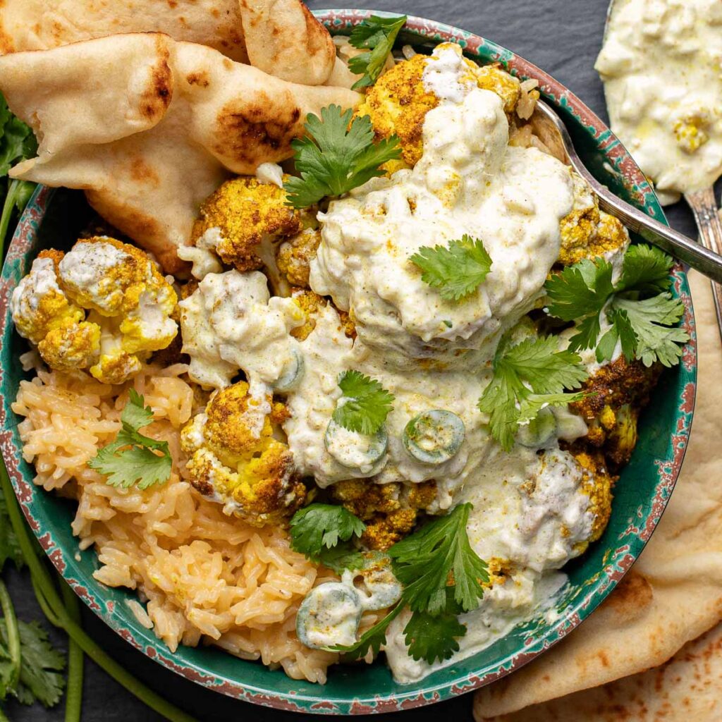 Indian cauliflower curry over coconut rice in a green bowl