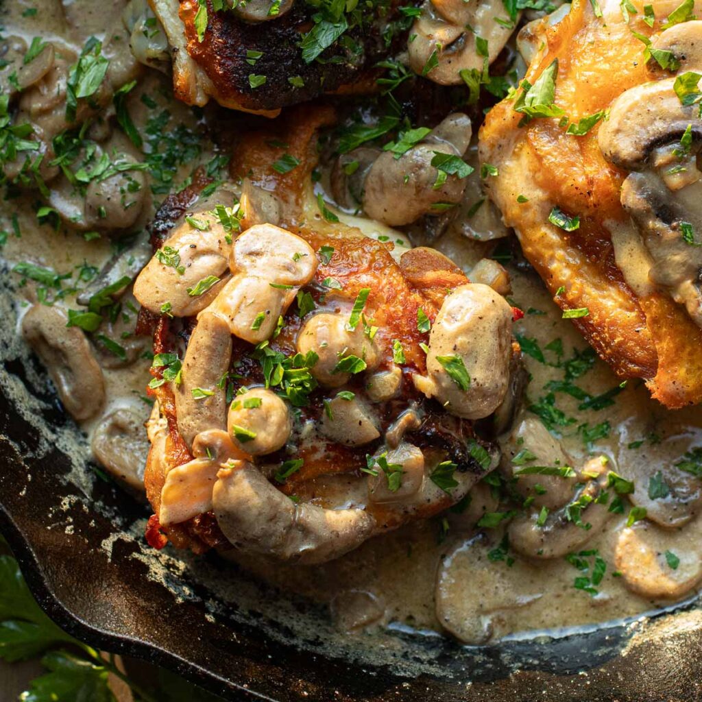 keto chicken thighs in mushroom cream sauce topped with fresh parsley
