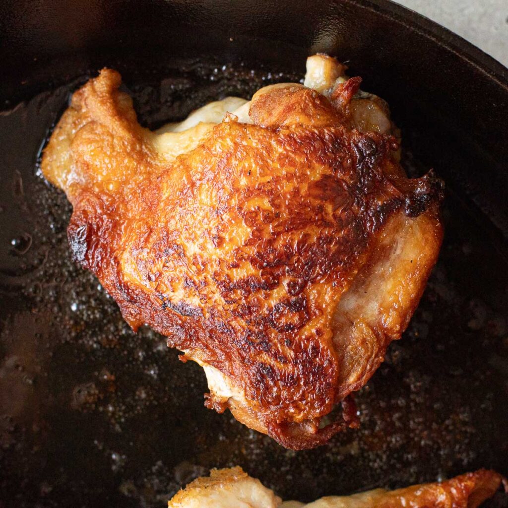 chicken thigh with crispy skin in a cast iron skillet