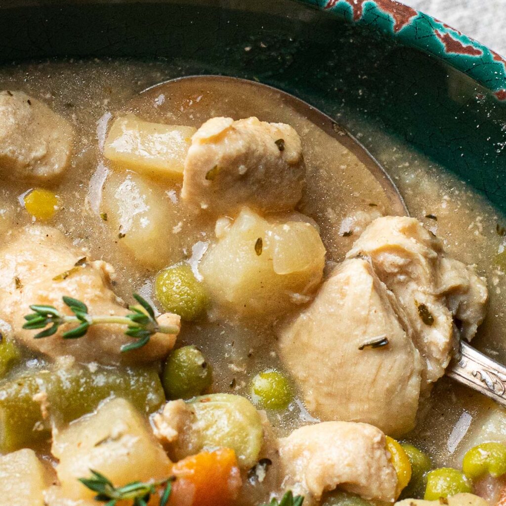 close up view of chicken vegetable stew with green peas and carrots