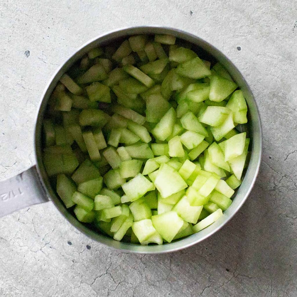 diced cucumber in a metal measuring cup