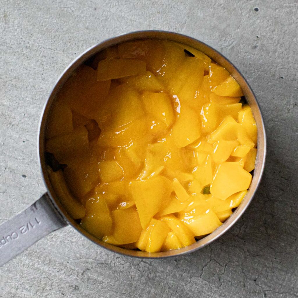 sliced mangoes in a metal measuring cup