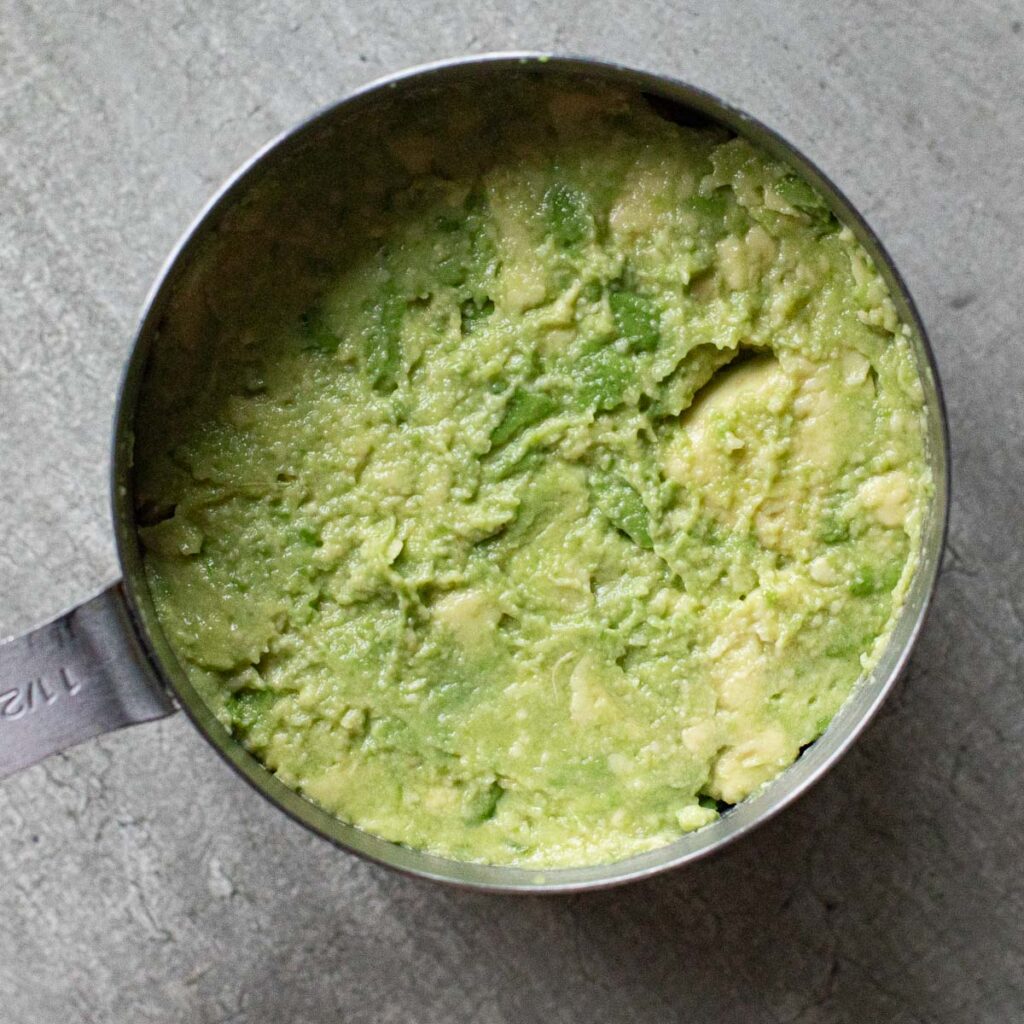 mashed avocado in a metal measuring cup