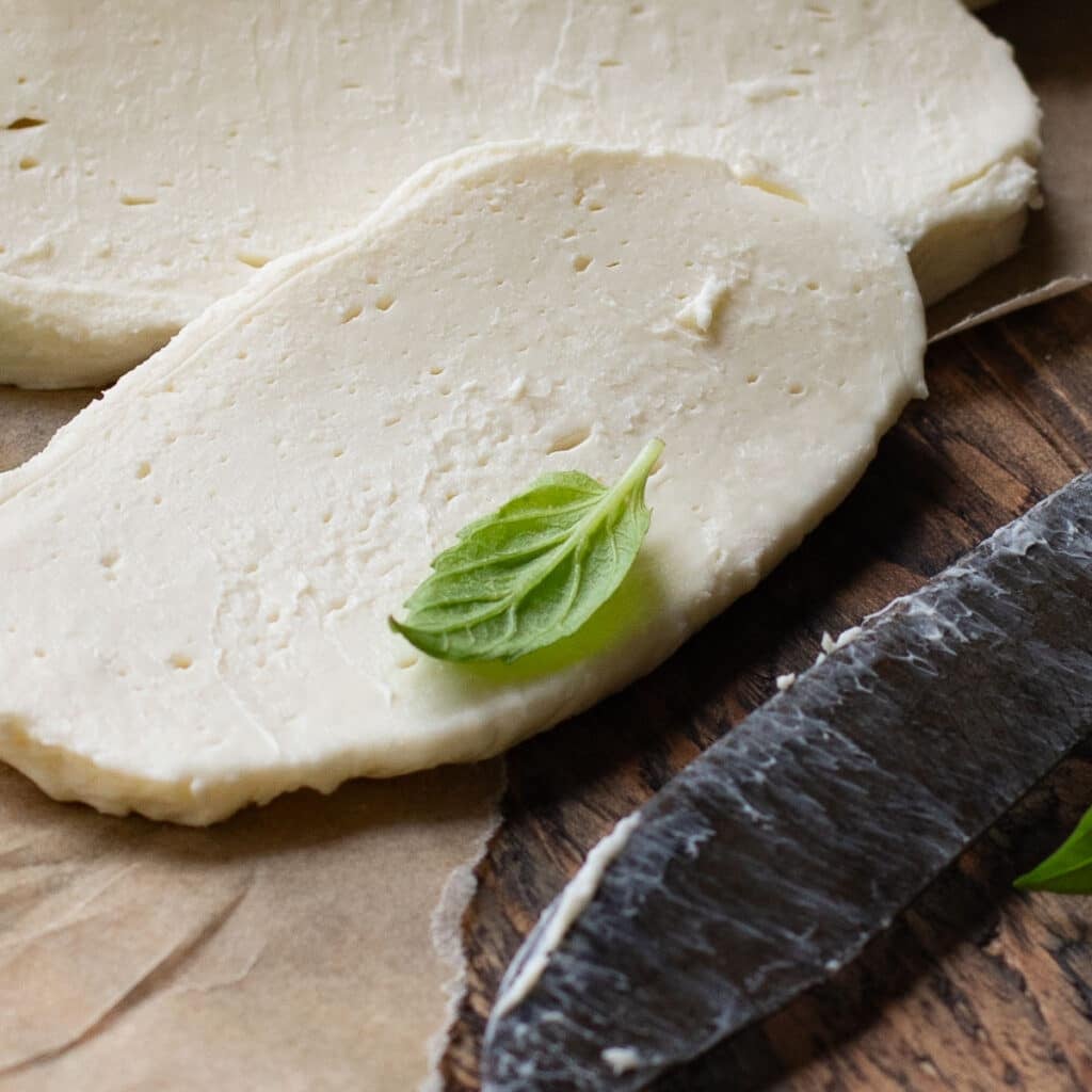 a slice of homemade mozzarella cheese with a basil leaf 