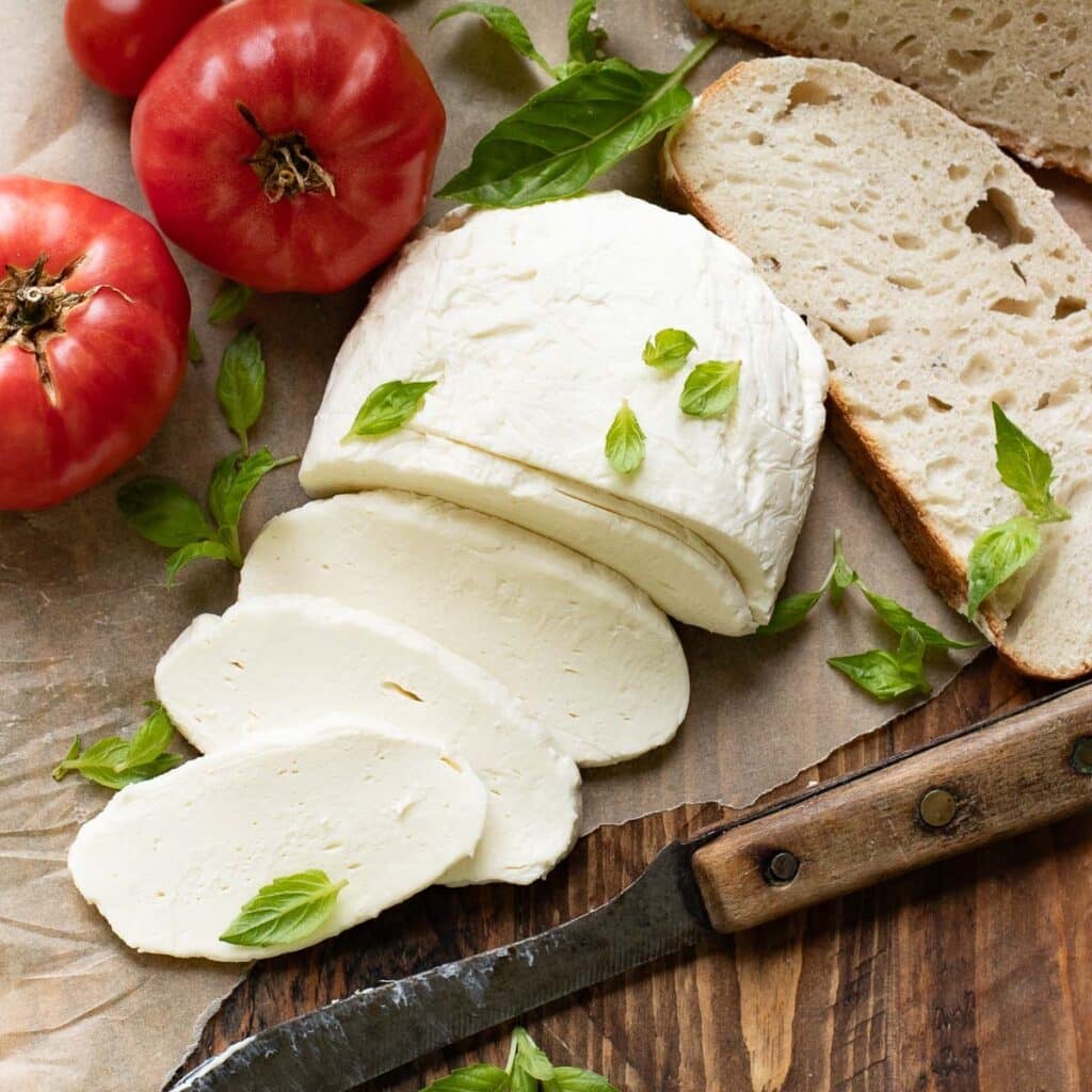 overhead view of a ball of homemade mozzarella topped with fresh basil leaves