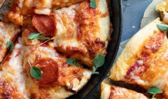 pizza in a cast iron pan next to a pan pizza on parchment paper