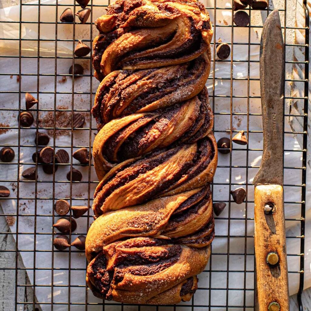 overhead view of a baked loaf of chocolate babka bread on a wire rack