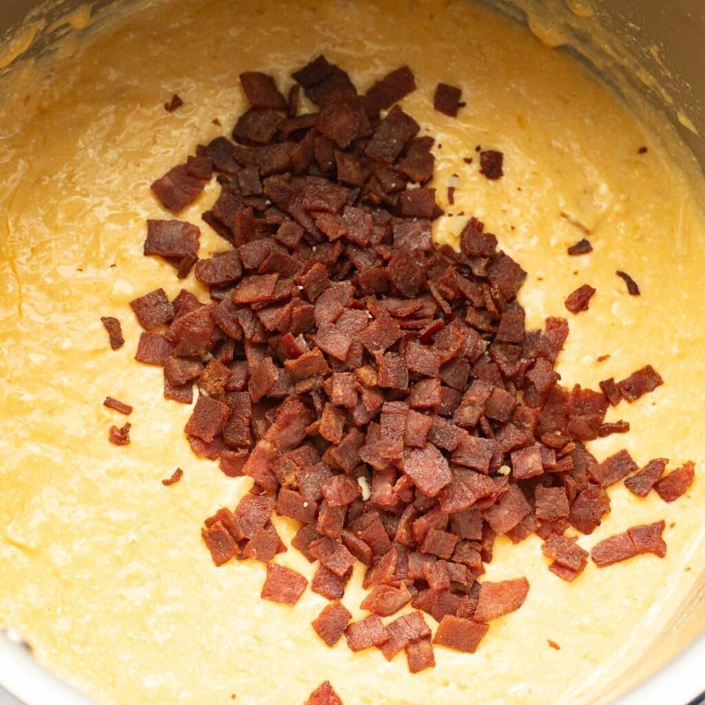 bacon bits on top of a cheese sauce in a pot