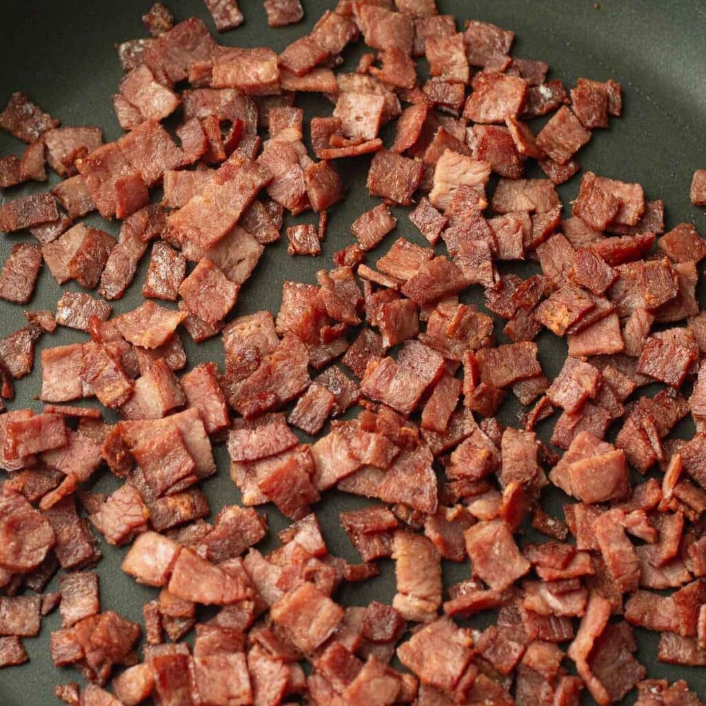 diced bacon cooking in a pan