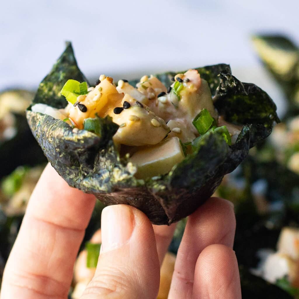 a hand holding one sushi cup