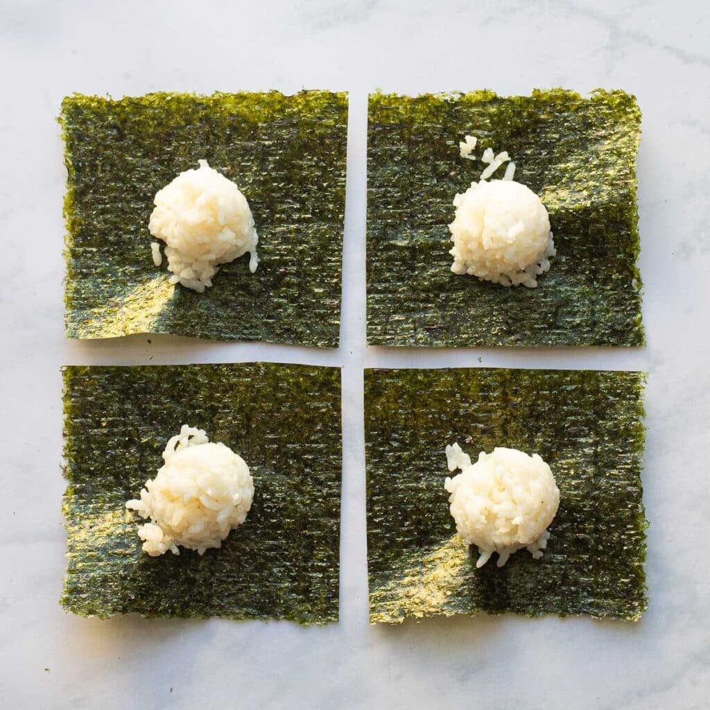 four squares of seaweed topped with rounds of sushi rice