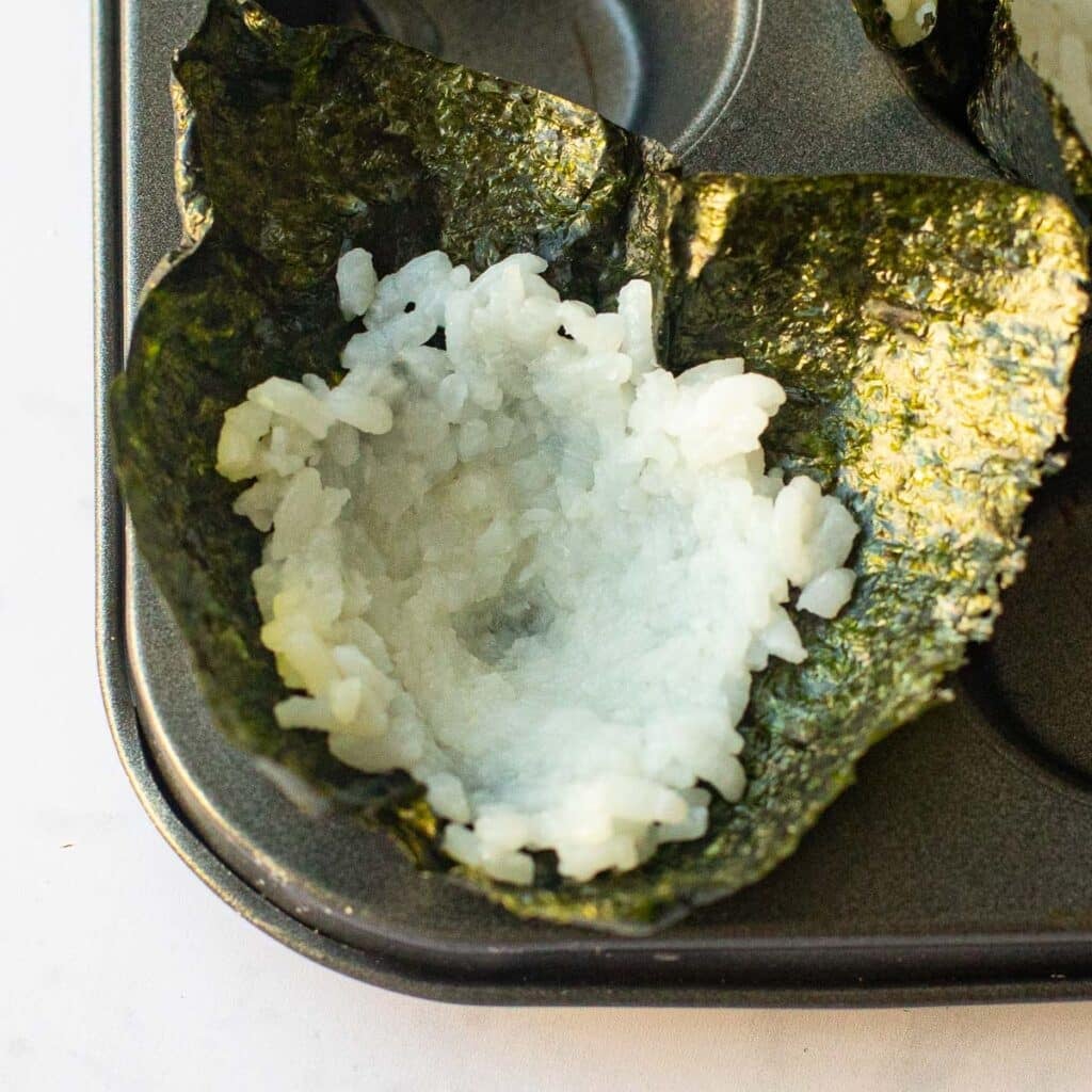 sushi rice pressed into a nori square in a mini muffin tin