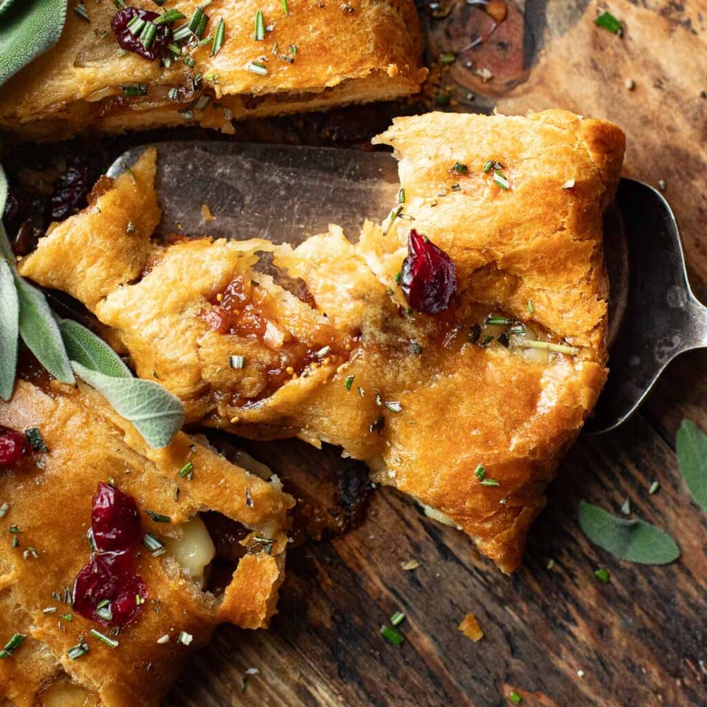 a slice of brie crescent roll wreath on a silver pie server