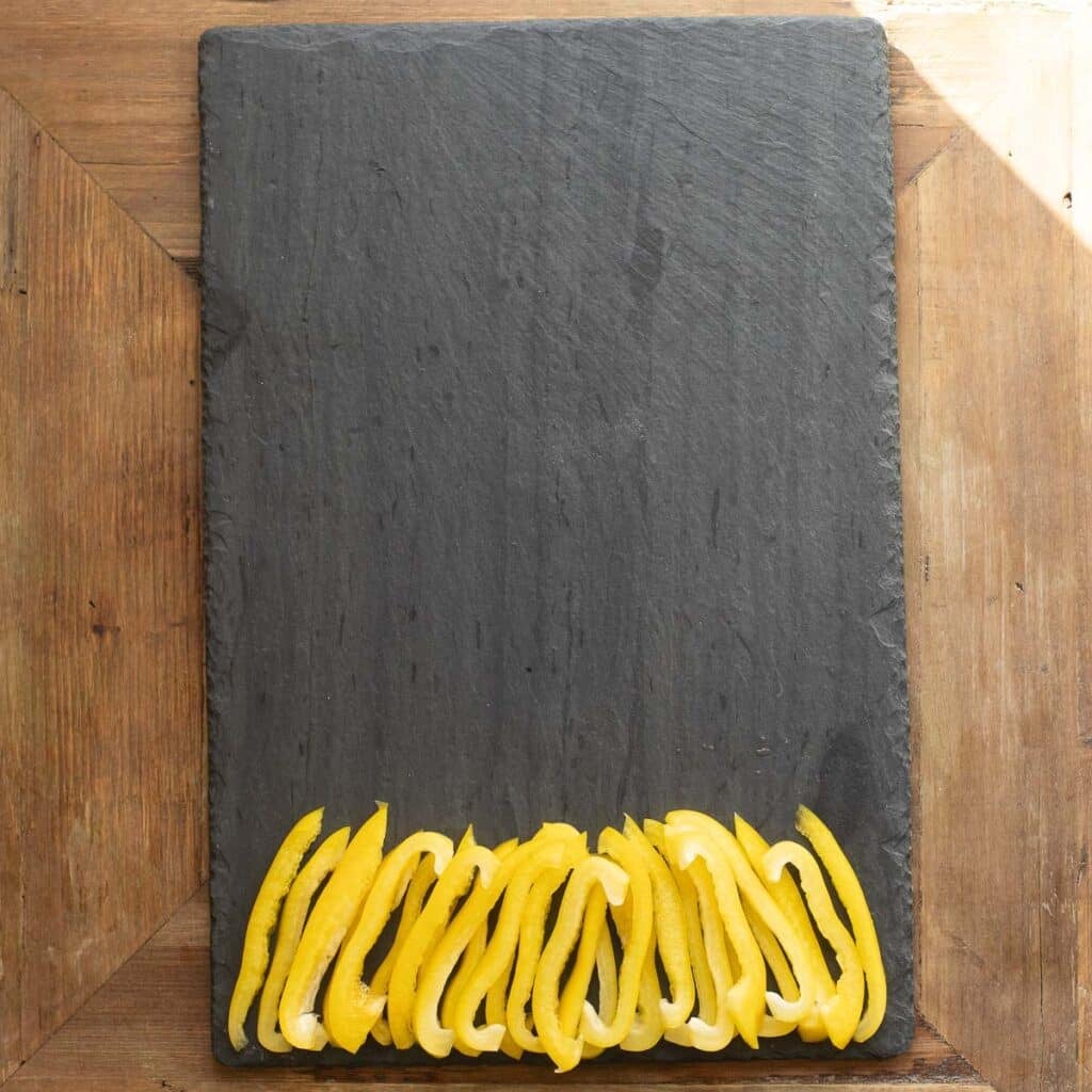 yellow bell pepper strips arranged on a black serving board