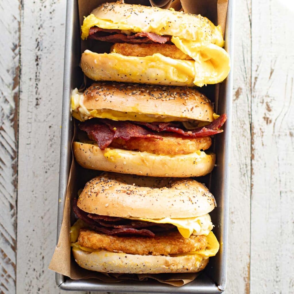 three breakfast bagel sandwiches arranged in a loaf pan