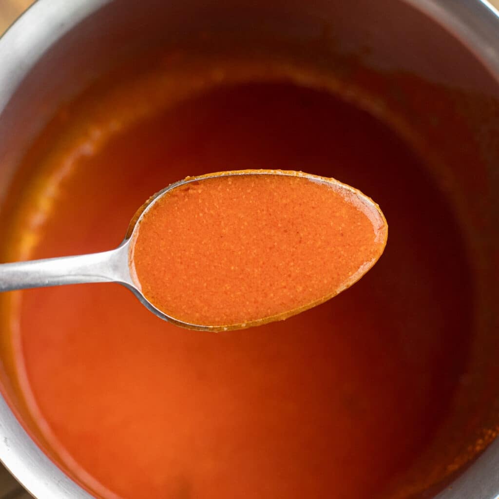 Buffalo wing sauce on a silver spoon