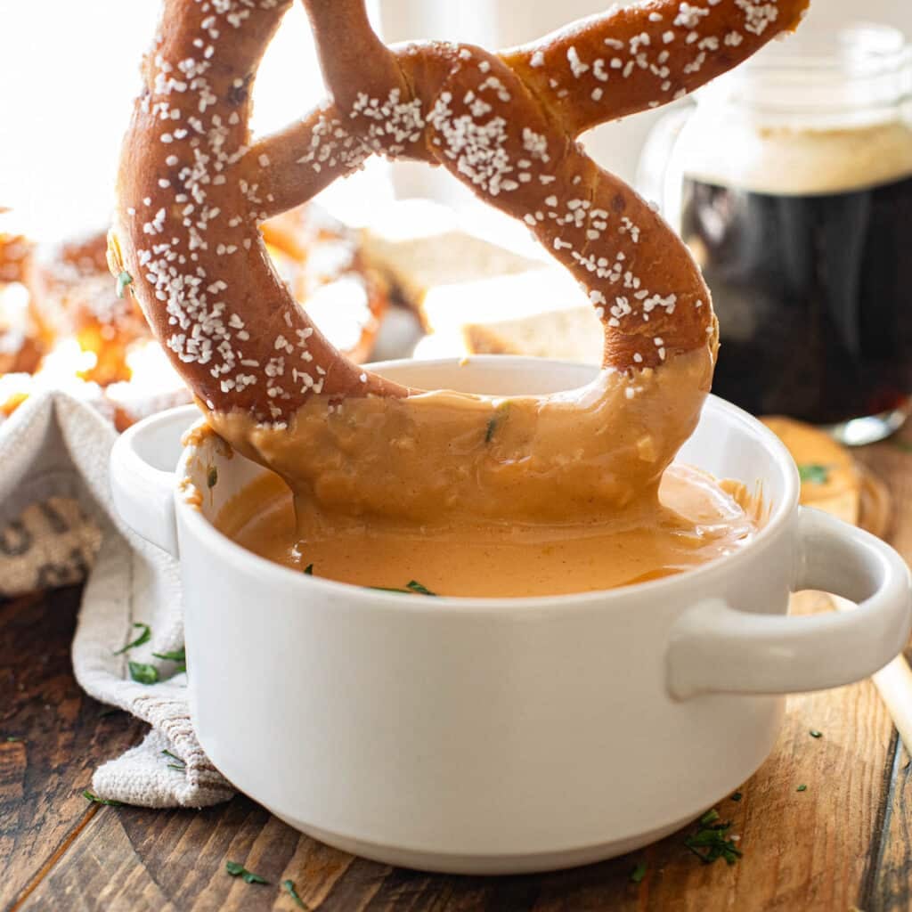 a soft pretzel dipping into Guinness cheese dip