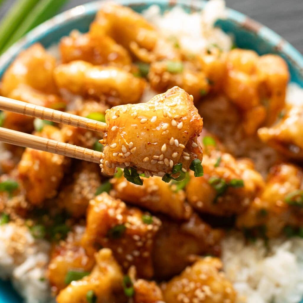 chopsticks holding a piece of honey butter chicken