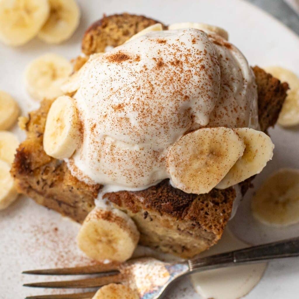 banana bread bread pudding topped with a scoop of vanilla ice cream and sliced bananas