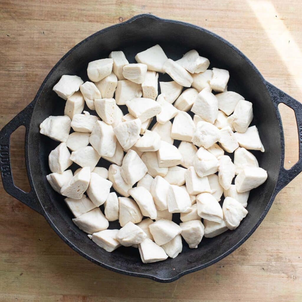quartered biscuit dough arranged in a cast iron pan