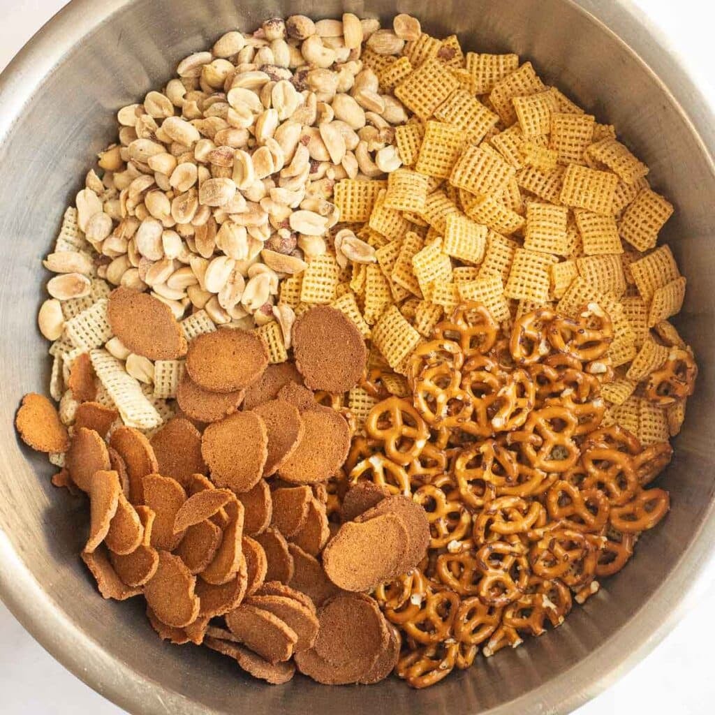 Chex cereal, peanuts, bagel chips and pretzels in a mixing bowl