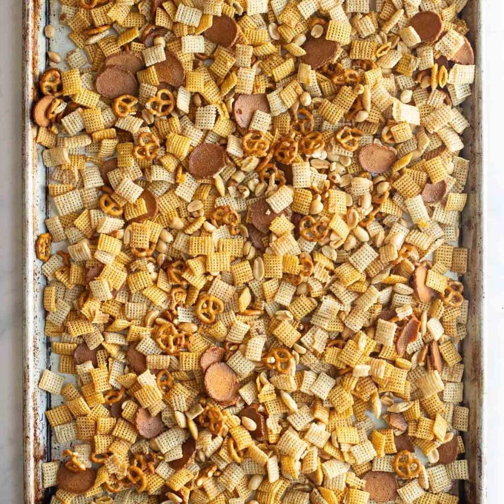 seasoned Chex mix spread onto a baking sheet