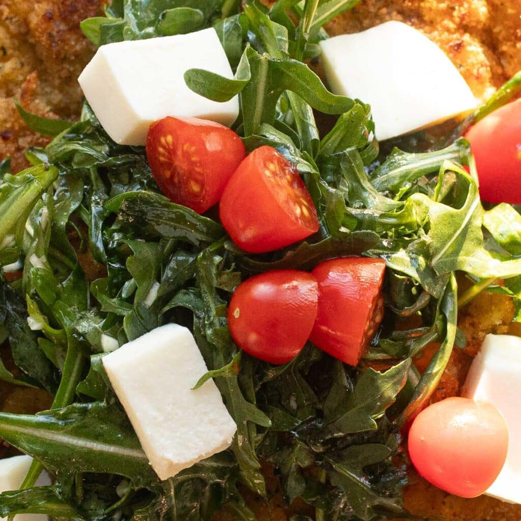 arugula salad on top of chicken cutlets