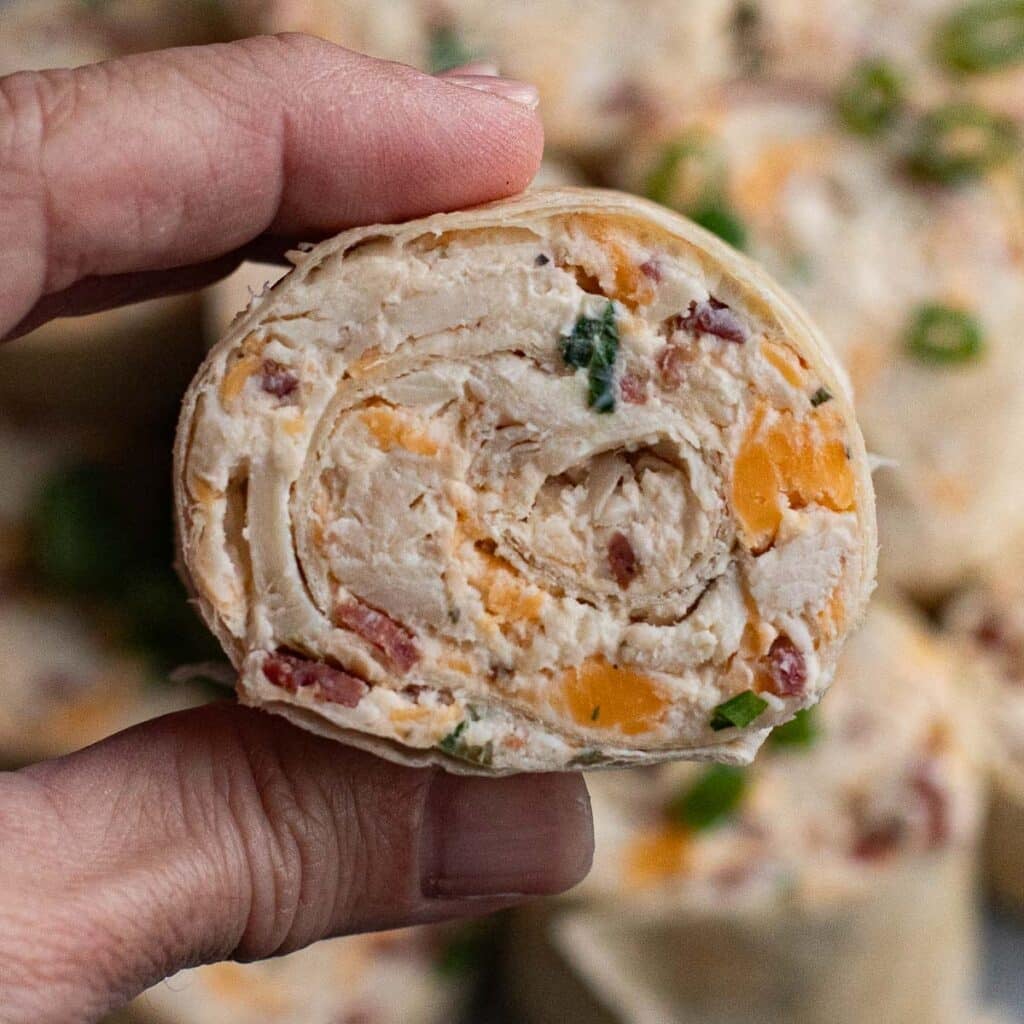 a hand holding a crack chicken pinwheel