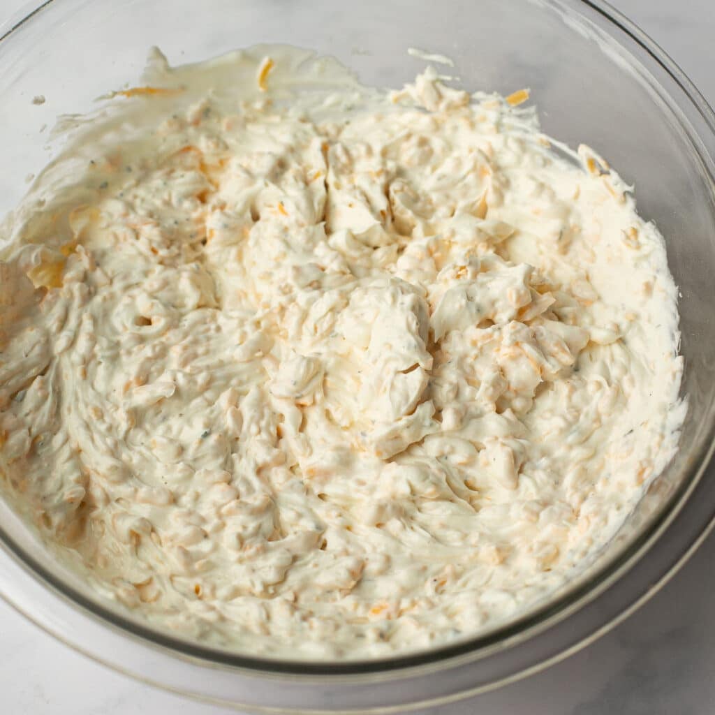 whipped cream cheese, sour cream, yogurt and cheese in a glass bowl