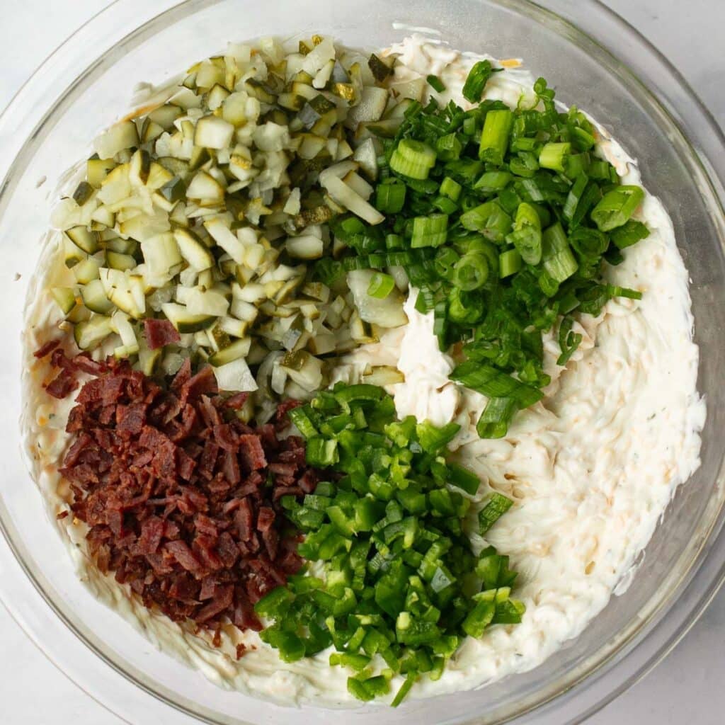 chopped pickles, scallions, diced bacon and jalapeno peppers in a glass mixing bowl