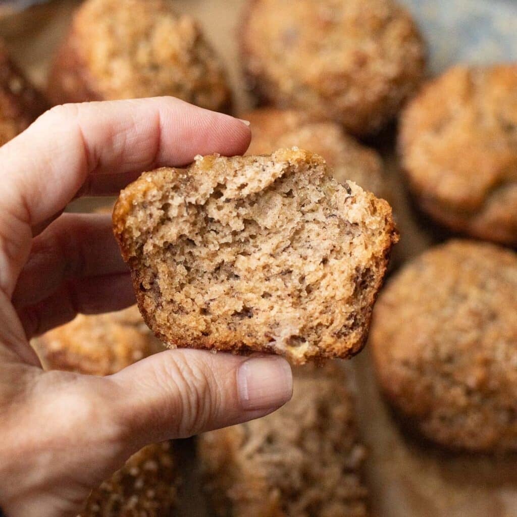 a hand holding half of a gluten free banana bread muffin