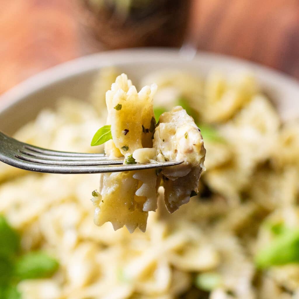 a fork holding chicken and pesto pasta
