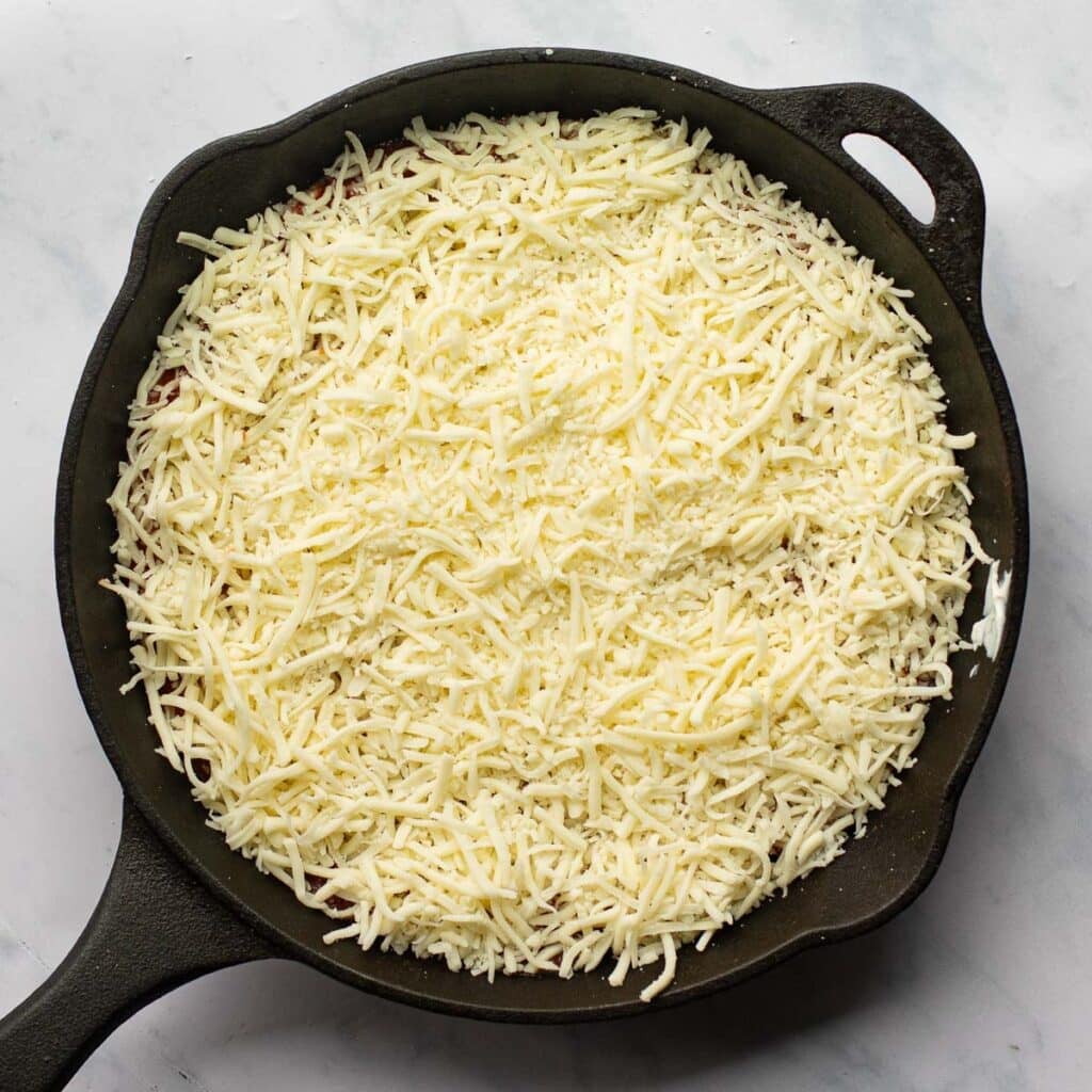 shredded mozzarella cheese in a cast iron skillet