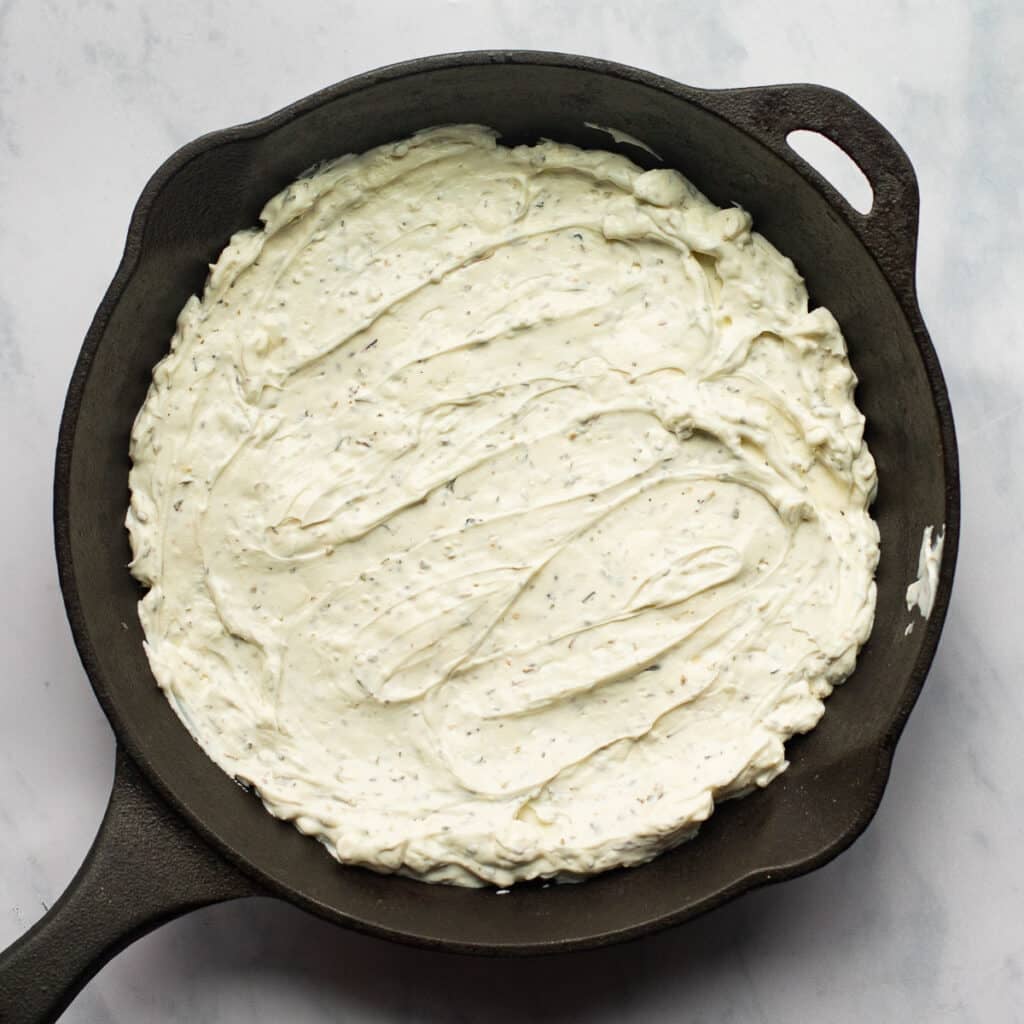 seasoned cream cheese spread in a cast iron skillet