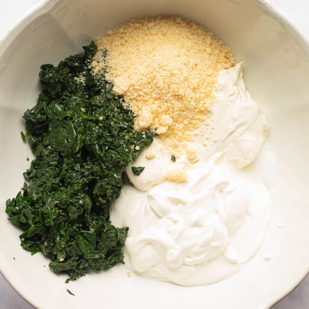 sauteed spinach, parmesan cheese and sour cream in a mixing bowl