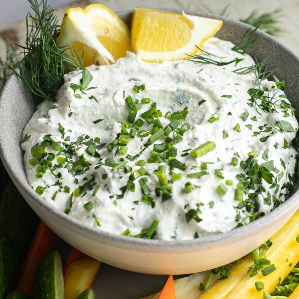 cottage cheese ranch dip in a gray bowl topped with fresh chives and lemon wedges