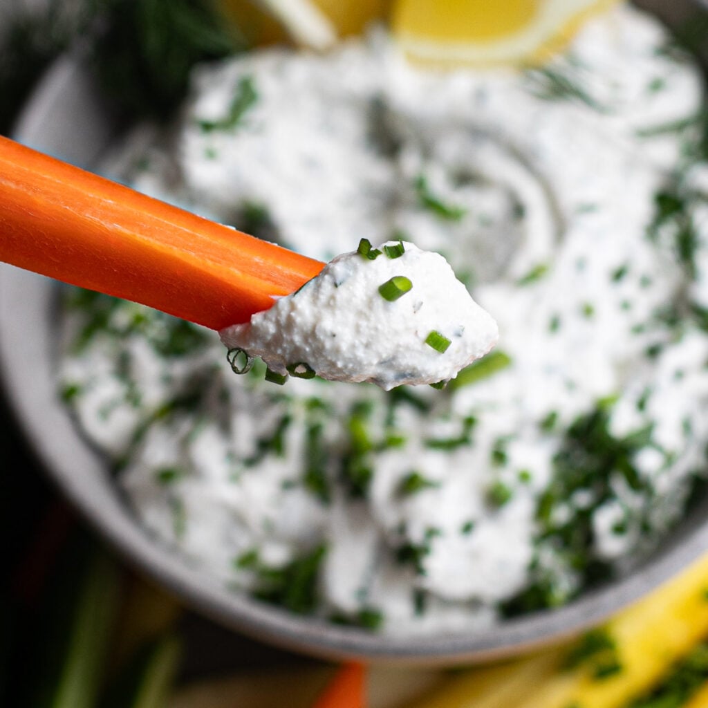 a carrot stick with cottage cheese ranch dip on it
