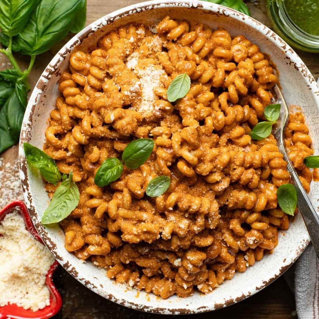 pasta with tomato pesto sauce in a white bowl