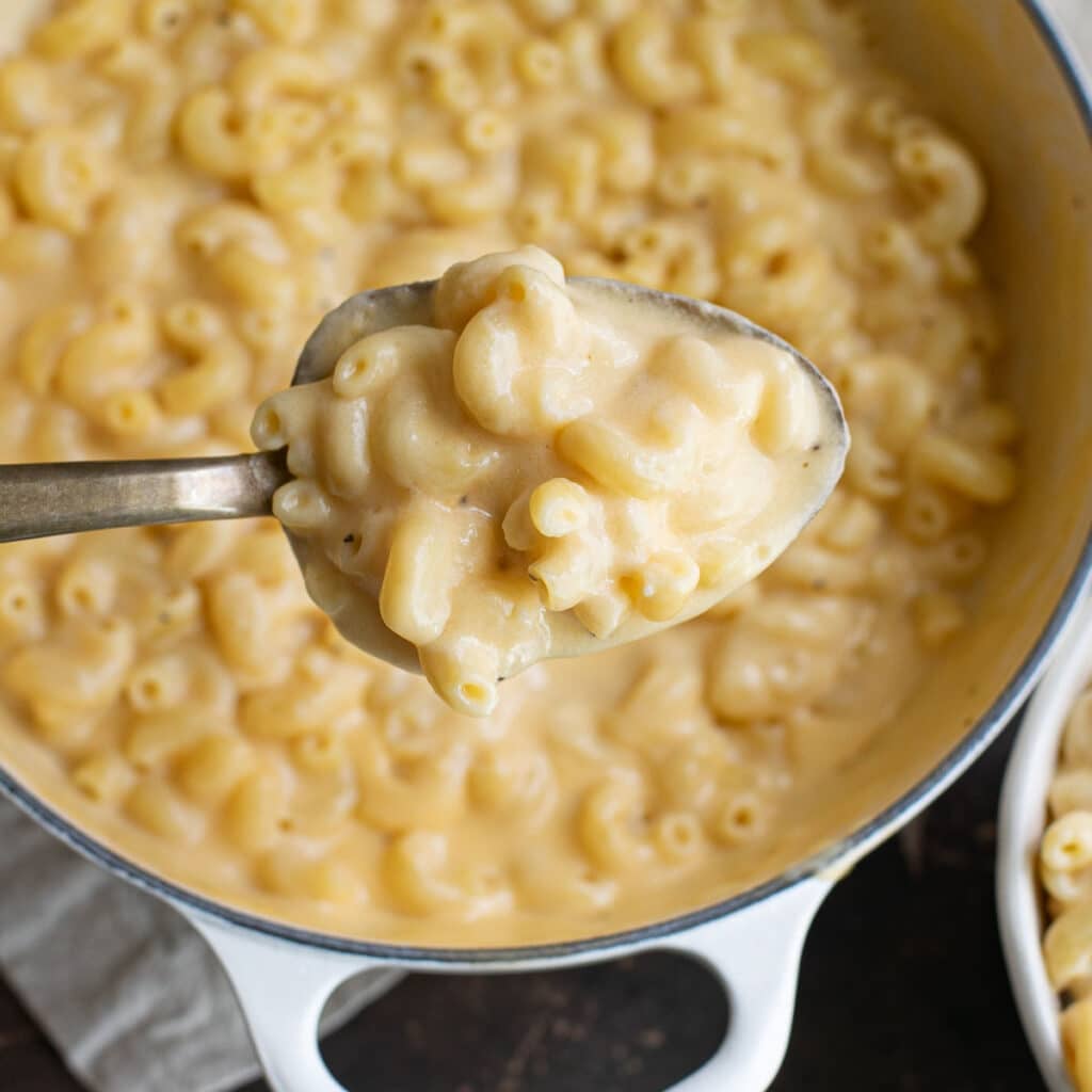 a large serving spoon holding homemade kraft mac and cheese